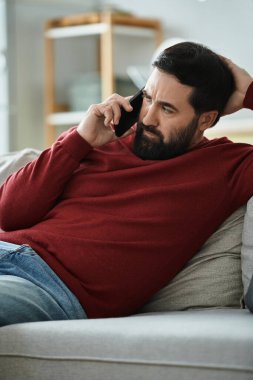 Günlük kıyafetlerini giymiş yaşlı bir adam dinlenirken düşünceli bir telefon görüşmesi yapıyor..