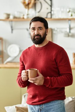 Çekici bir son sınıf öğrencisi şık bir mutfakta dikilirken sıcak bir bardaktan yudumluyor..