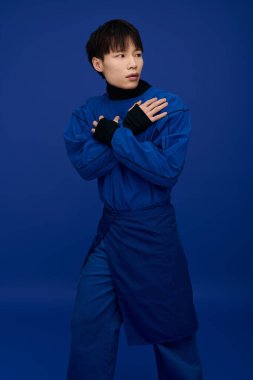 Şık, mavi elbiseli genç, yakışıklı bir Asyalı dramatik bir ifadeyle rahatça poz veriyor..