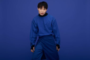 Çekici bir Asyalı genç adam modern moda sergiliyor, azimle cesur bir duruş sergiliyor..