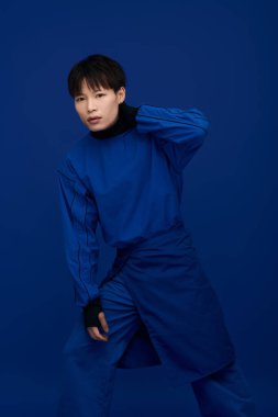 Kendine güvenen genç bir Asyalı zarif bir şekilde mavi bir elbise içinde poz veriyor..