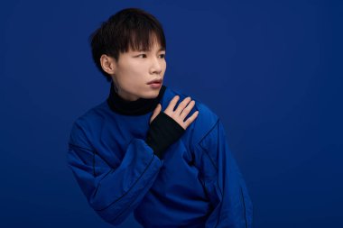 Şık mavi bir elbise giyen yakışıklı genç bir adam zarif ve düşünceli bir poz sergiliyor..