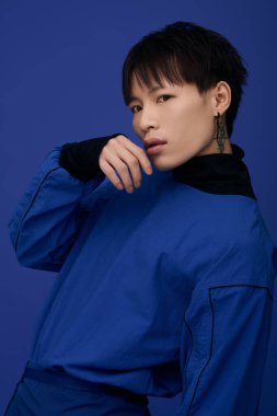 Yakışıklı genç Asyalı bir adam kendine güven ve karizma saçan şık mavi bir kıyafet sergiliyor..