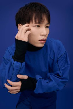 Mavi kıyafetli yakışıklı genç bir Asyalı canlı bir arka plana kafa yoruyor..