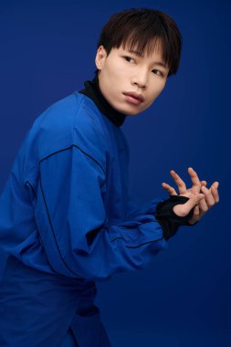 Çekici bir Asyalı genç, kendine güveni tam, cesur mavi bir elbiseyle eşsiz tarzını sergiliyor..