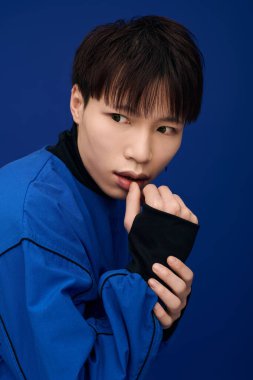 Yakışıklı, genç Asyalı bir adam şık mavi elbiseler giyer, düşünceli görünür..