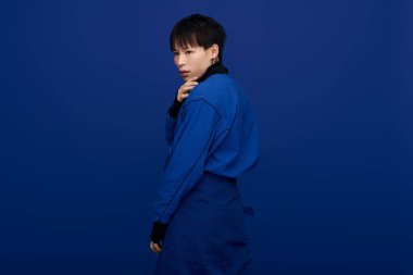 Yakışıklı Asyalı genç bir adam dikkat çekici mavi bir elbiseyle modern stili sergiliyor..