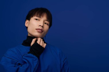 Şık giyinmiş yakışıklı Asyalı genç adam büyüleyici bir bakışla kendine güveniyor.