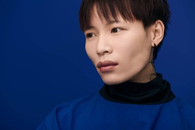 Genç, yakışıklı Asyalı bir adam özgüven ve cazibe saçarak düşünceli bir şekilde bakıyor..