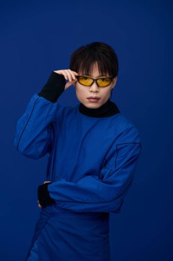 Kendine güvenen mavi elbiseli ve güneş gözlüklü Asyalı genç adam moda tarzını sergiliyor..