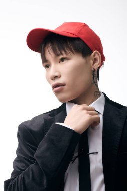 Keskin giyimli Asyalı genç adam kravatını minimalist bir ortama göre ayarlıyor..