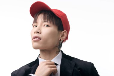 Şık bir Asyalı genç adam, kendine güvenen bir cazibeyle takım elbisesini ve şapkasını düzeltir..