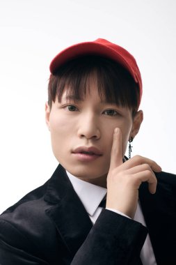 Genç yakışıklı Asyalı bir adam, kırmızı şapkalı, takım elbiseli ve çekici bir şekilde poz veriyor..