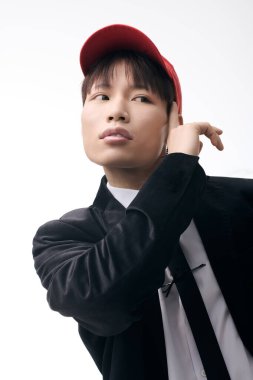 Yakışıklı genç adam sade bir arka plana karşı duruyor, modaya uygun bir tarz ve karizma sergiliyor.