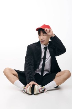 Çekici genç adam modern modaya özgüveniyle bakıyor. Stüdyoda rahatça oturuyor..