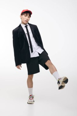 Genç bir adam dinamik bir poz verir. Resmi ve günlük kıyafetlerin karışımı, gülümser..