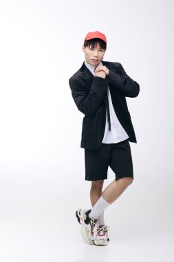 Tarz sahibi genç adam sade bir arkaplanda poz veriyor, terzi kıyafetiyle cazibesini sergiliyor..