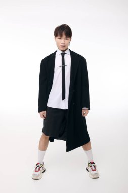 Yakışıklı bir Asyalı genç adam kendine güvenerek parlak bir stüdyoda çarpıcı bir kıyafet modelliyor..