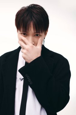 Genç yakışıklı Asyalı bir adam neşeli bir hareketle poz veriyor, karizma yayıyor ve tarzını içeride gösteriyor..