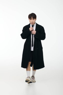 Yakışıklı, şık giyinmiş genç bir Asyalı kravatını kendine güvenle düzeltir..