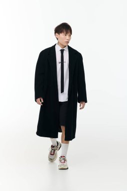 Modern kıyafetli genç, yakışıklı Asyalı bir adam minimalist bir alana güven yayar..