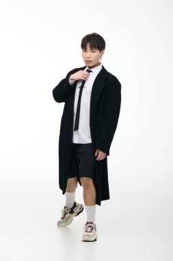 Siyah ceketli ve kravatlı şık genç bir adam temiz beyaz bir arkaplana karşı güven yayıyor..