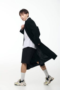 Yakışıklı Asyalı genç adam kendine güvenerek minimalist bir ortamda yürüyor ve kendine has tarzını sergiliyor..