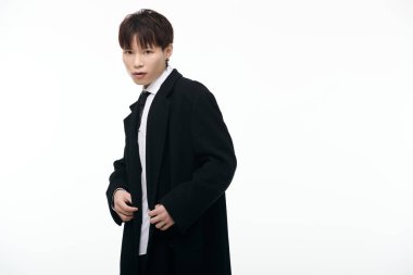 Genç ve çekici bir Asyalı erkek zarif bir şekilde poz verirken şık bir siyah cekete güvenir..