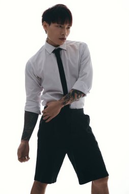 Yakışıklı bir Asyalı kendine güvenen bir duruş sergiliyor, eşsiz stilini ve dövme sanatını sergiliyor..