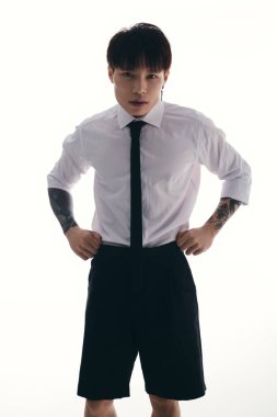 Çekici Asyalı genç bir adam dimdik ayakta duruyor, özgüven ve özgüven ile eşsiz bir kıyafet modelliyor..