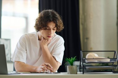 Yakışıklı genç adam masasında oturuyor, şık bir ofis düzeninde işine konsantre oluyor..