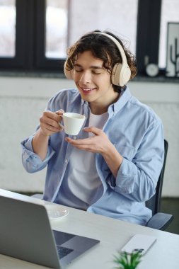 Kahvesini yudumlarken yakışıklı, genç bir profesyonel gülümseme, parlak bir ofiste işine dalmış..