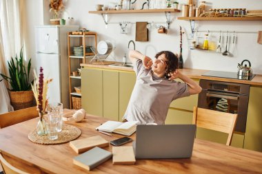 İyi görünümlü genç bir adam çalışırken ve çevresinin tadını çıkarırken rahat ofisinde esniyor..