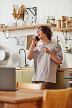 Genç, çekici bir adam şık bir ofiste kahve içerken telefonla konuşuyor..