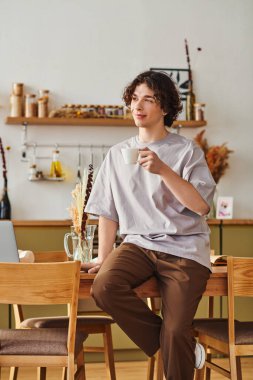 Kıvırcık saçlı şık genç adam kahveyi seviyor ve rahat bir ofise yansıyor..