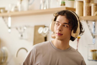 Kulaklıklı yakışıklı genç adam çağdaş bir ofis alanında yaratıcı işler yapıyor.