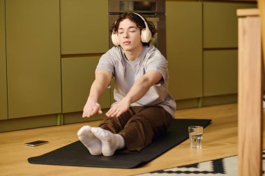 Yogaya odaklanan genç adam, parlak ve çağdaş bir mutfakta mindere uzanıyor..