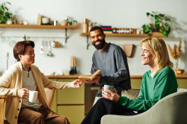 Genç erkekler rahat bir yaşam alanında birlikte kitap okurken keyifli bir sohbetten hoşlanırlar..