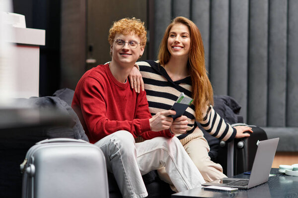 A young couple happily preparing for their travels in a chic hotel lobby.