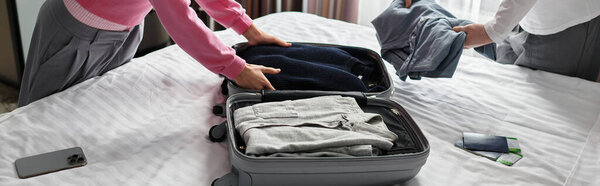 A loving couple prepares their luggage, sharing tender moments in a warm hotel setting.