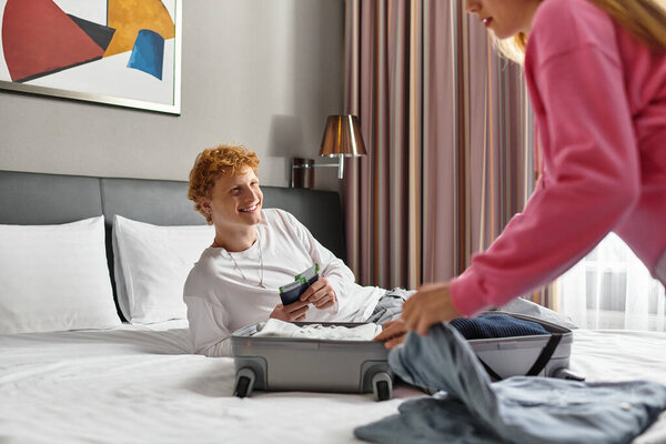 A loving couple shares a warm moment in their hotel room as they unpack for a delightful trip.