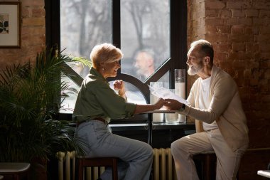 İki orta yaşlı birey kahkaha ve sohbeti paylaşıyor, kalıcı anılar yaratıyorlar..