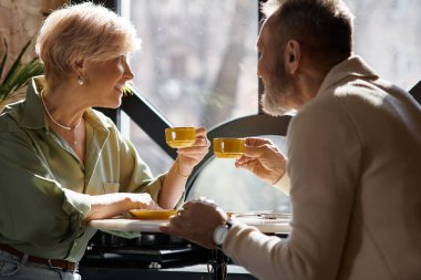 Olgun bir çift, büyüleyici bir kafe ortamında kahve içerken sıcak bir sohbetten zevk alır..