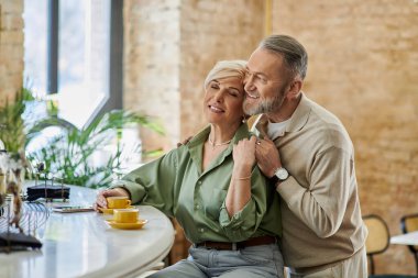 Orta yaşlı bir çift sıcacık bir kafede kahve yudumlarken sıcak bir anı paylaşıyor..