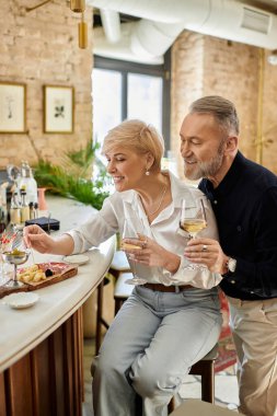 Olgun bir çift, şık bir bar ortamında içki ve tatlı tapas eşliğinde romantik bir randevudan hoşlanır..