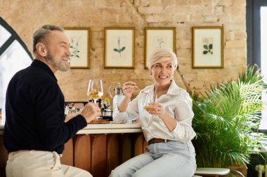 Orta yaşlı bir çift şık bir barda şarap içerken sıcak dakikalardan zevk alır..