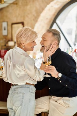 Olgun bir çift, sıcak bir bar atmosferinde içkilerini yudumlarken birlikte keyifli bir anın tadını çıkarıyor..