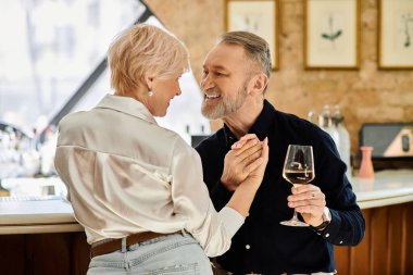 Orta yaşlı bir erkek ve kadın birlikte içkilerinin tadını çıkarırken özel bir anın tadını çıkarırlar..