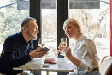 Olgun bir çift güneşli bir öğleden sonra keyifli bir randevudan zevk alır, gülümseme ve içkileri paylaşırlar..