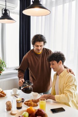 Eşcinsel çift, sıcak ve davetkar bir atmosferle çevrili bir kahvaltıyı paylaşıyor..